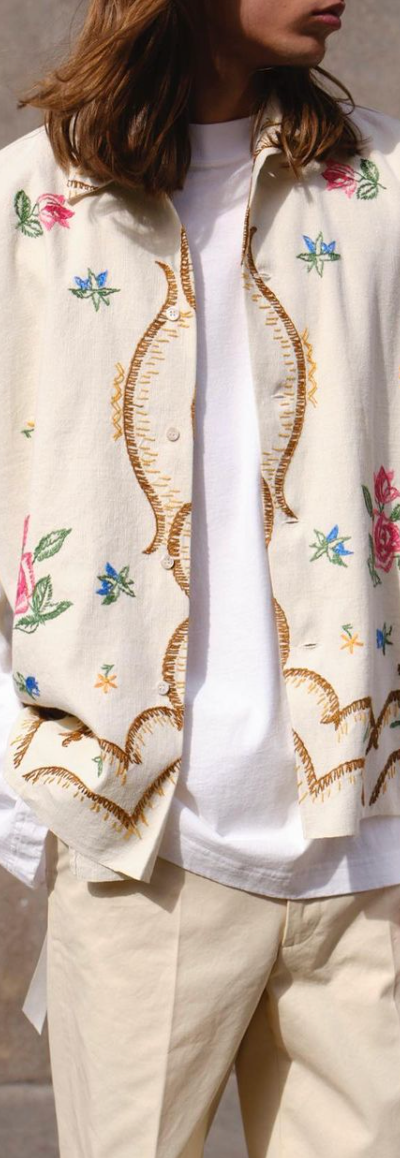 A man with long hair wearing a Damir Doma beige floral button up with biege pants and a white longsleeve