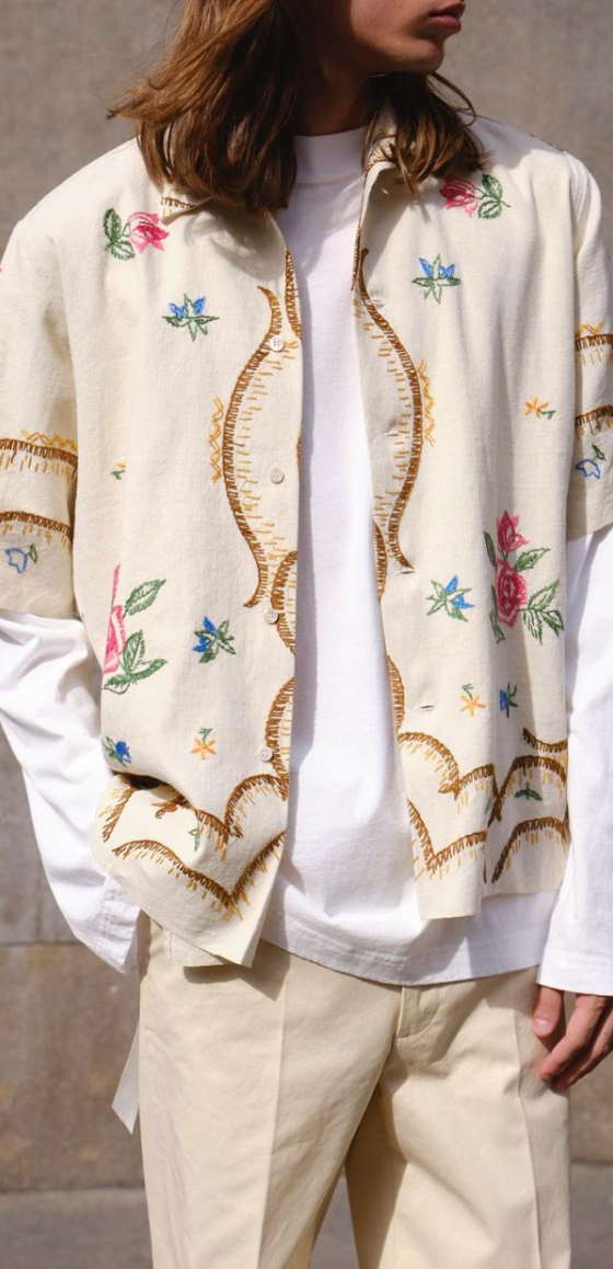 A man with long hair wearing a Damir Doma beige floral button up with biege pants and a white longsleeve