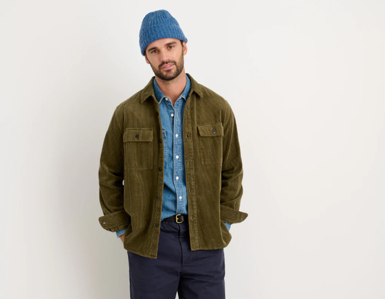 A man wearing a Alex Mill oliver green button up with a blue beanie and navy blue pants