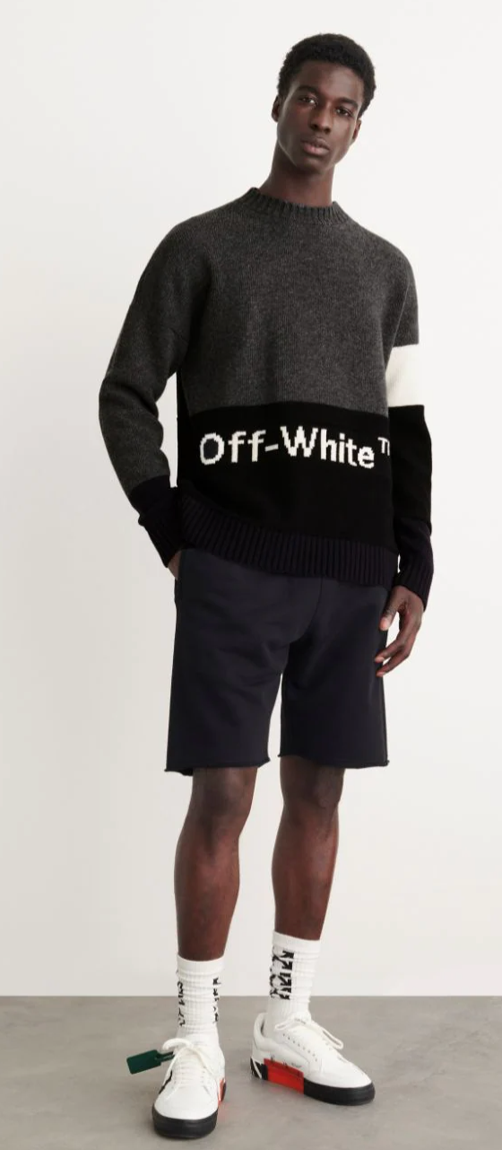 A man wearing a black Off-White sweater, black shorts and branded Off-white socks