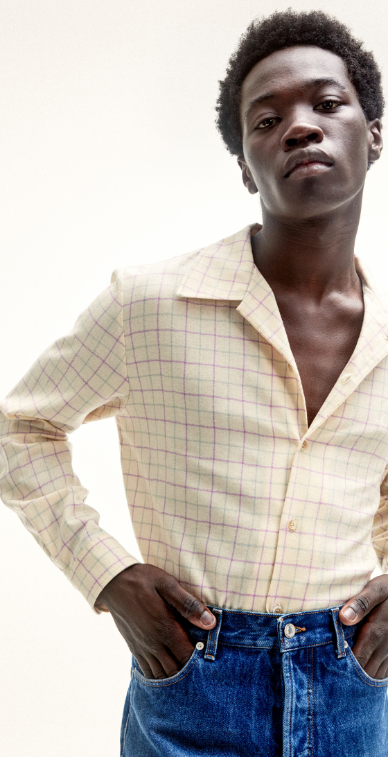A man wearing Sefr jeans and a yellow striped long-sleeve button-up