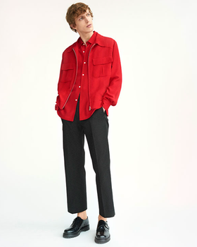 A man wearing a red Sandro button-up with a red over-jacket and black pleated pants