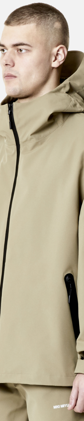 A man wearing a MKI Myuki beige technical jacket with matching pants