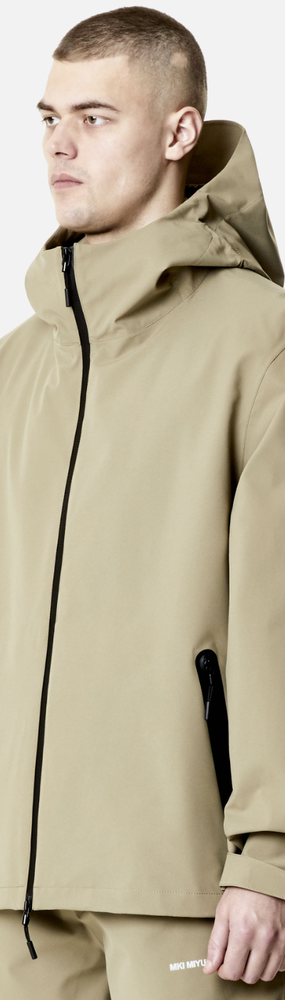 A man wearing a MKI Myuki beige technical jacket with matching pants