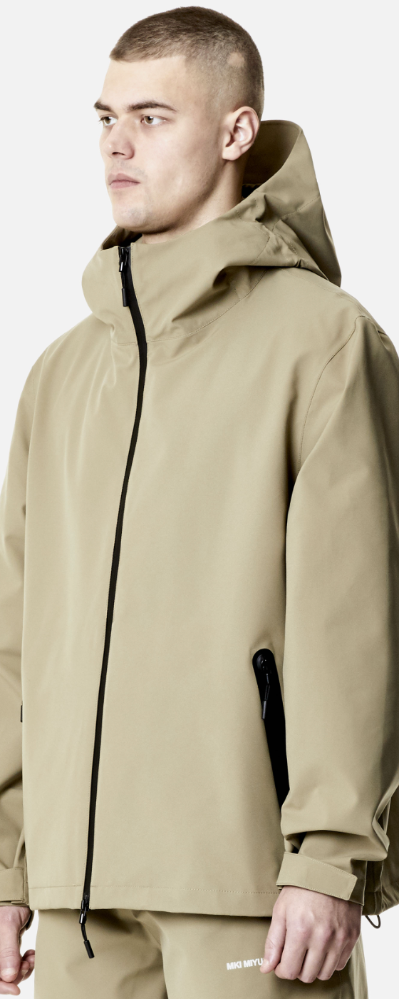 A man wearing a MKI Myuki beige technical jacket with matching pants