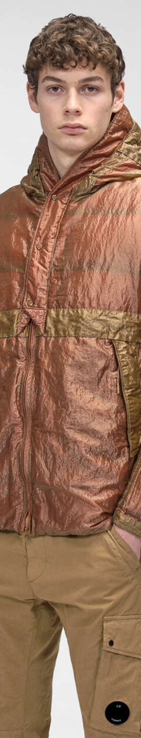 A man wearing a CP Company red and brown technical jacket and brown pants