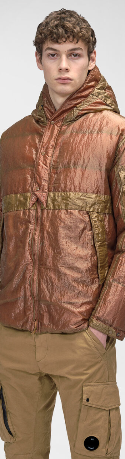 A man wearing a CP Company red and brown technical jacket and brown pants