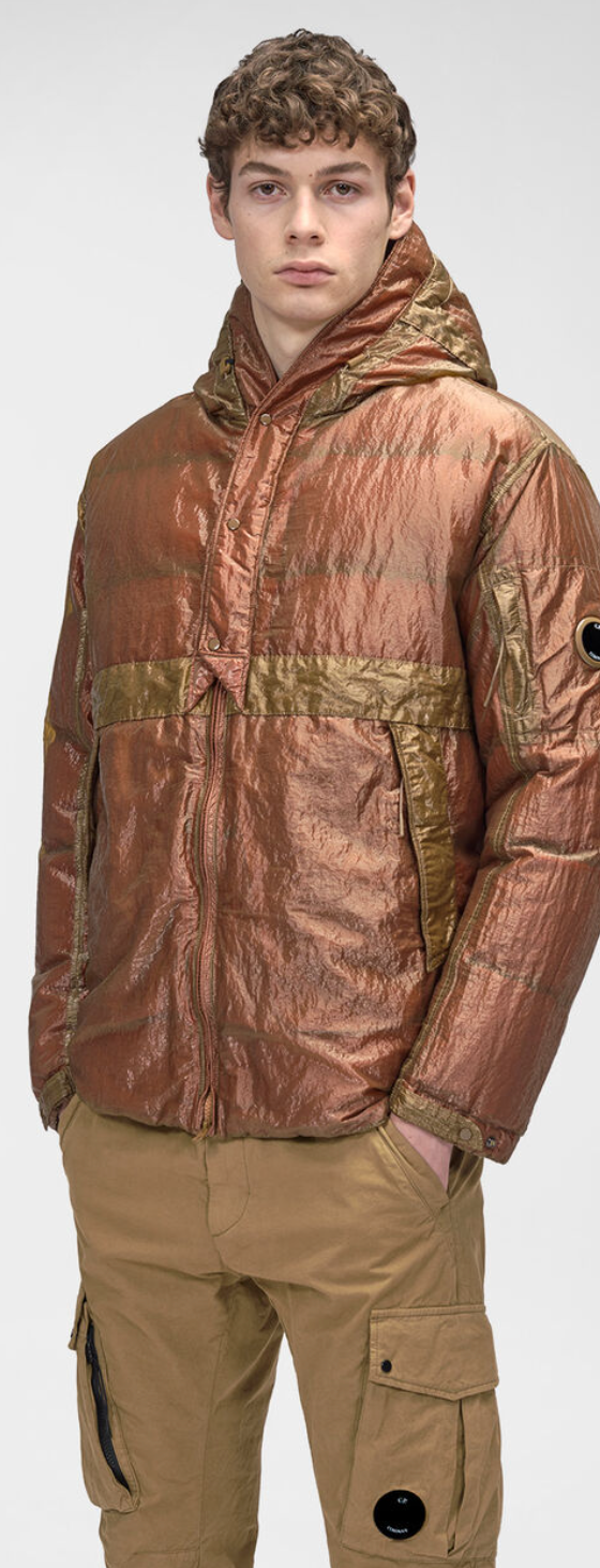 A man wearing a CP Company red and brown technical jacket and brown pants