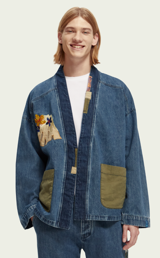 A man wearing a Scotch & Soda Japanese style denim jacket and matching pants with floral designs sewn on