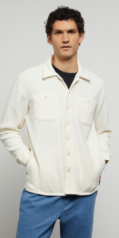 A man wearing a plush Onia button-up with a black shirt underneath and blue-washed jeans