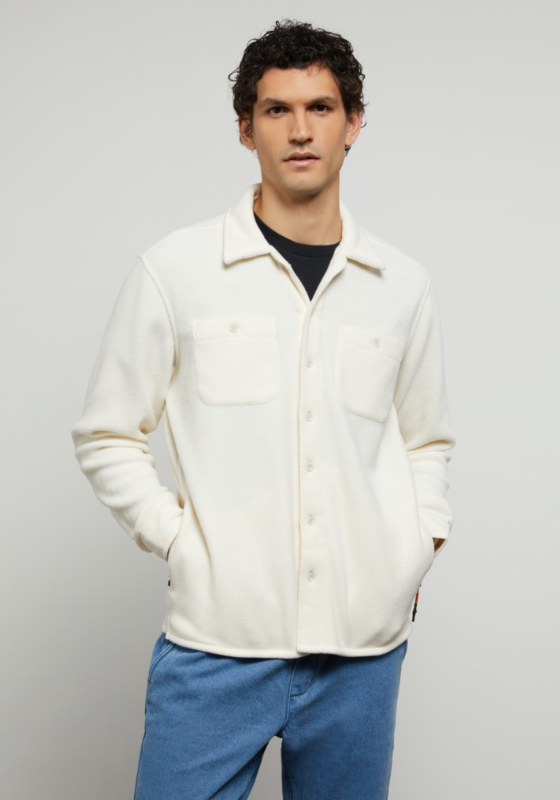 A man wearing a plush Onia button-up with a black shirt underneath and blue-washed jeans