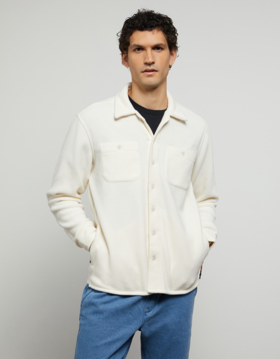A man wearing a plush Onia button-up with a black shirt underneath and blue-washed jeans