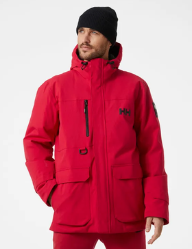 A man wearing a bright Red Helly Hanson winter Jacket with matching red pants and a black beanie
