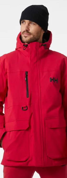 A man wearing a bright Red Helly Hanson winter Jacket with matching red pants and a black beanie