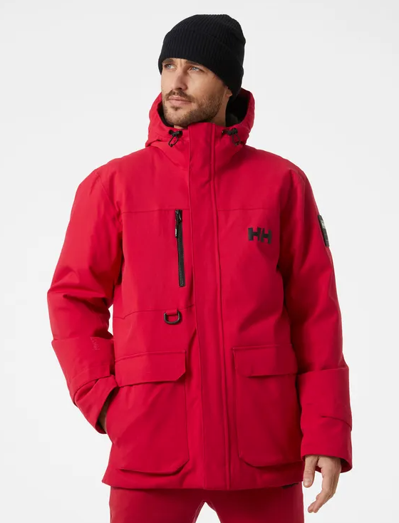 A man wearing a bright Red Helly Hanson winter Jacket with matching red pants and a black beanie