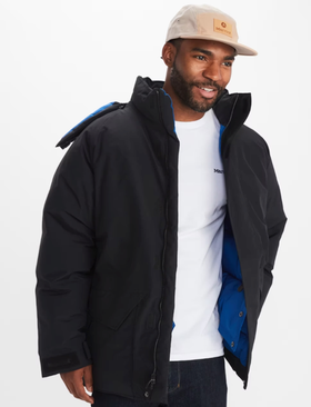 A man wearing a Marmot outfit feating a white t-shirt, black winter coat and a beige hat