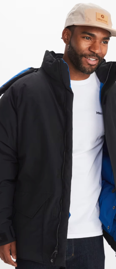 A man wearing a Marmot outfit feating a white t-shirt, black winter coat and a beige hat