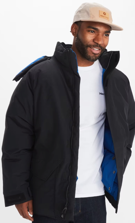 A man wearing a Marmot outfit feating a white t-shirt, black winter coat and a beige hat