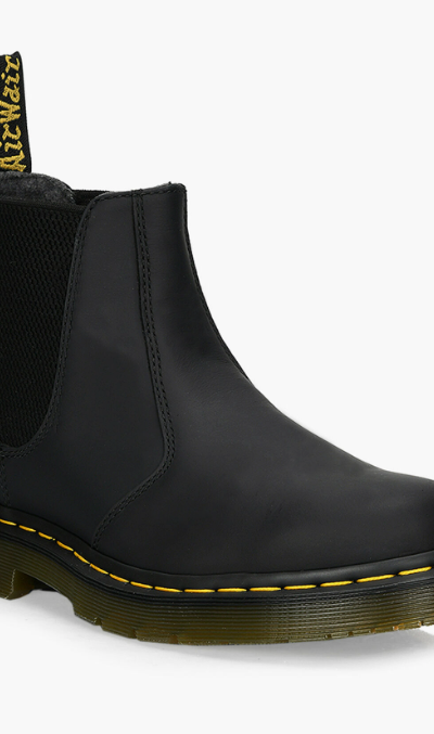 A black pair of slip-on Dr. Martens boots on a white background