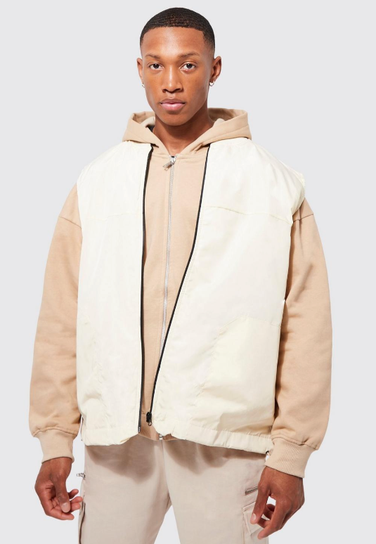 A man wearing a Boohooman cream vest and beige sweatshirt