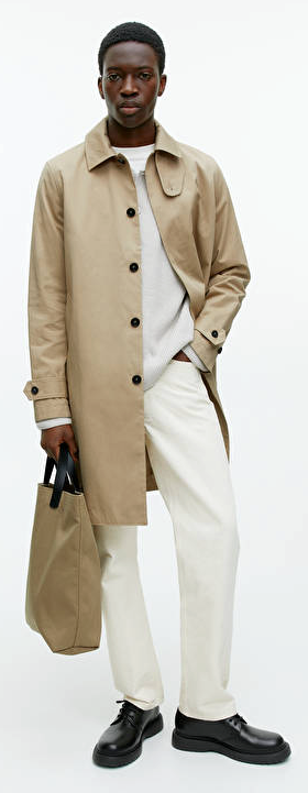 A man wearing a brown Arket trench coat and cream pants with black loafers