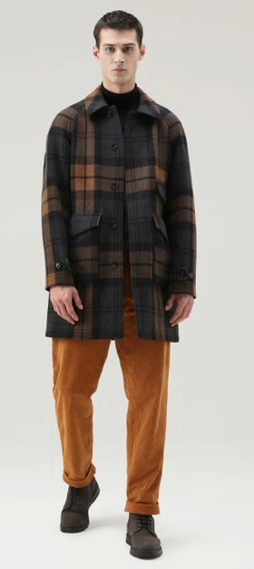 A man wearing a plaid Woolrich overcoat and brown pants