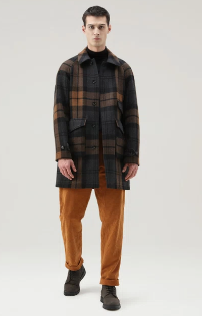 A man wearing a plaid Woolrich overcoat and brown pants