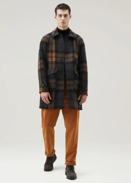 A man wearing a plaid Woolrich overcoat and brown pants