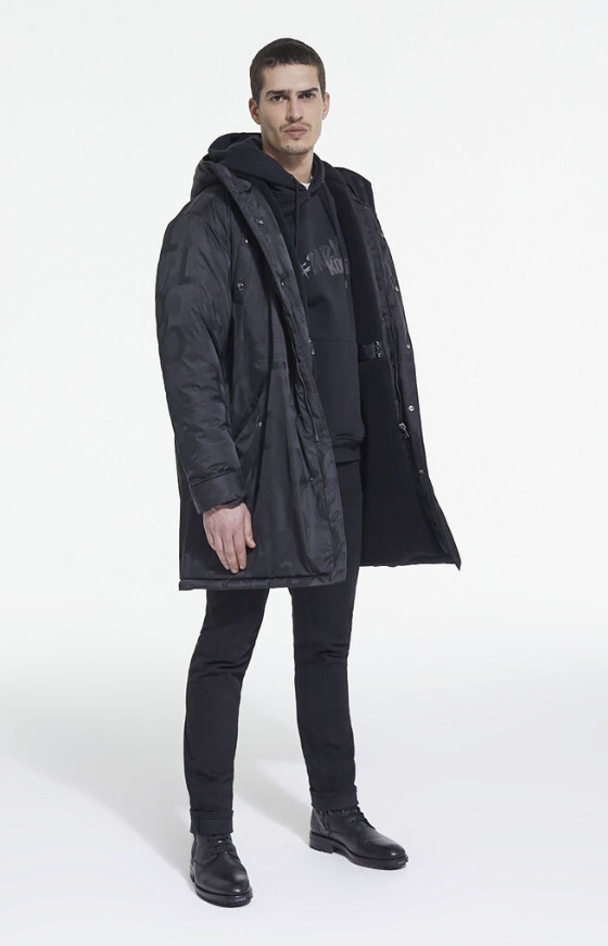 A man wearing The Kooples black jacket, with a black hoodie, pants and boots