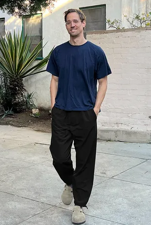 A man walking while wearing Outdoor Voices navy blue shirt and black pants