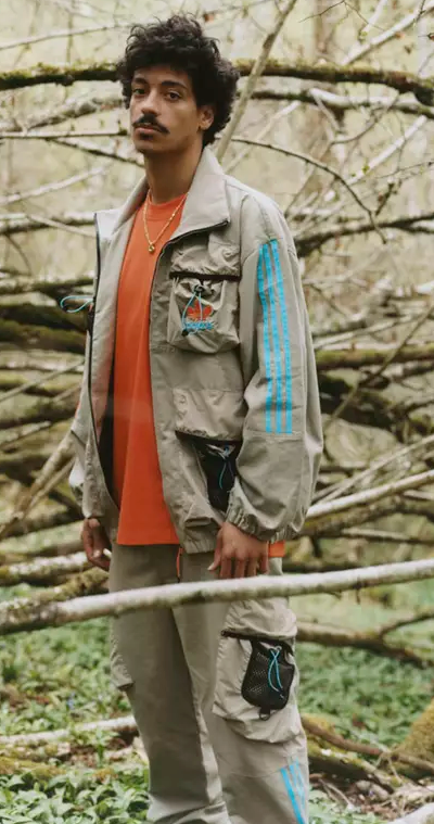 A man in the woods wearing an Adidas Palace collab outfit