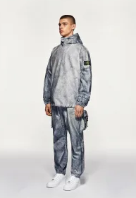 A man wearing a Stone Island futuristic looking tracksuit with white shoes