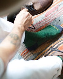 A man putting on a green Wigwam wool sock