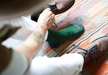 A man putting on a green Wigwam wool sock