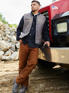 A man wearing a wrangler vest, button up and brown pants