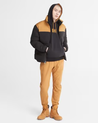 A man wearing a timberland outfit with a brown jacket, pants and boots