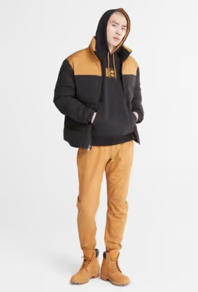 A man wearing a timberland outfit with a brown jacket, pants and boots
