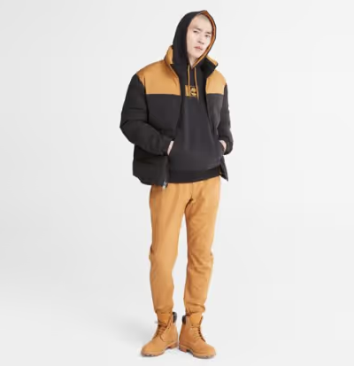 A man wearing a timberland outfit with a brown jacket, pants and boots