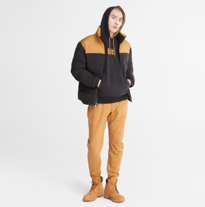 A man wearing a timberland outfit with a brown jacket, pants and boots