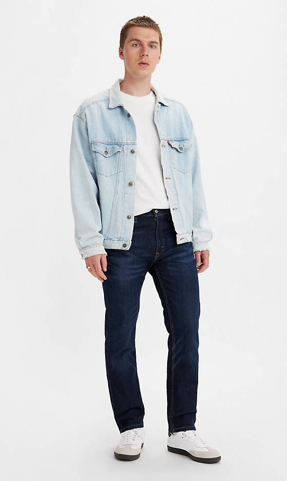A man wearing a denim Levis jacket, white t-shirt and black pants