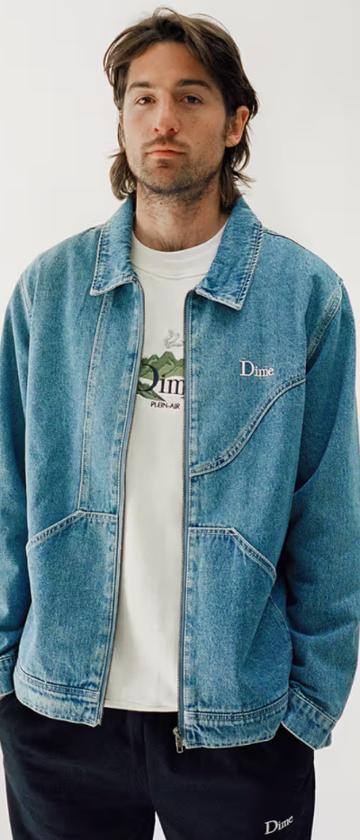 A man wearing a Dime denim jacket and a white t-shirt and navy blue pants