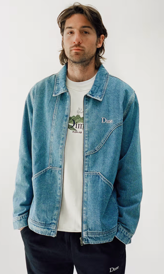A man wearing a Dime denim jacket and a white t-shirt and navy blue pants