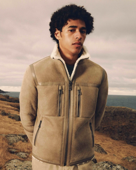 A man wearing a Belstaff sheepskin jacket with khaki pants