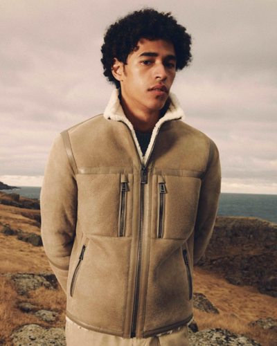 A man wearing a Belstaff sheepskin jacket with khaki pants