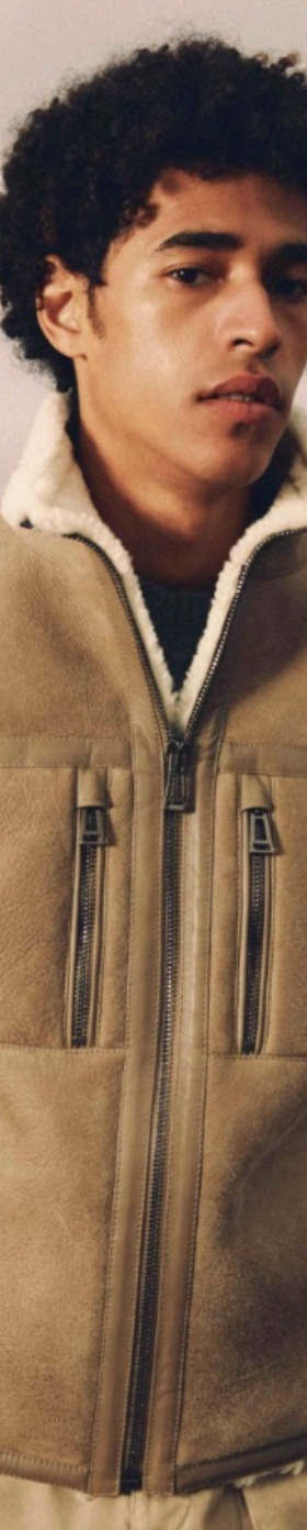 A man wearing a Belstaff sheepskin jacket with khaki pants