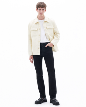 A man wearing a cream Filippa K overshirt, a white t-shirt and black slacks