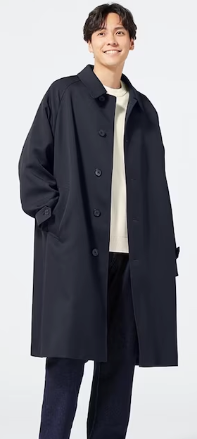 A man wearing a minamilist Gu navy blue overcoat, with a white shirt and navy blue pants