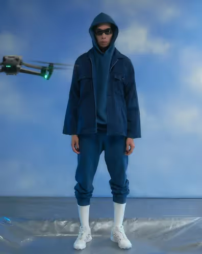 A man wearing a blue blue japan overcoat with a blue hoodie and blue sweatpants