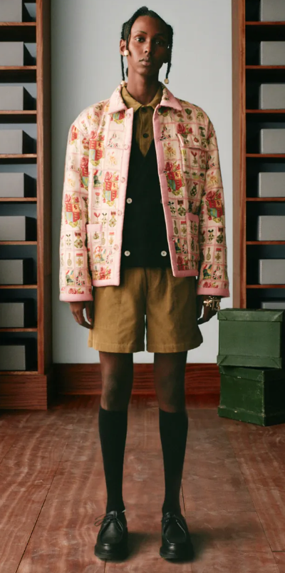 A man wearing a pink floral print Bode jacket, brown shorts and high black socks