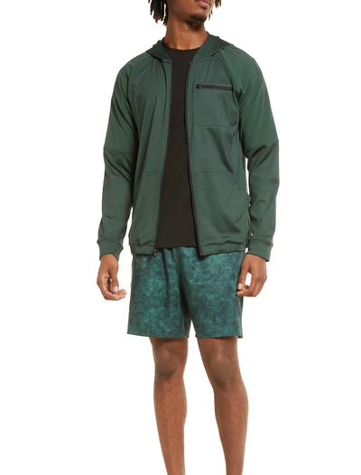 A man standing in a green Zella by Nordstrom jacket and shorts